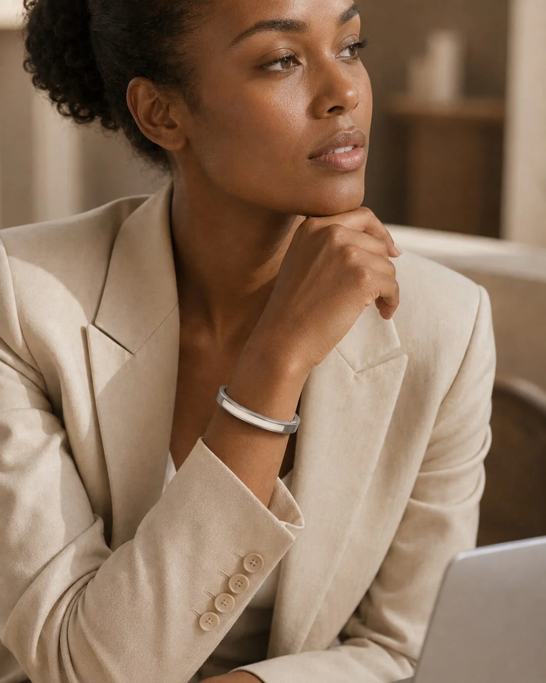 Woman in a beige blazer wearing an inactive JUVEIL bangle at her wrist.