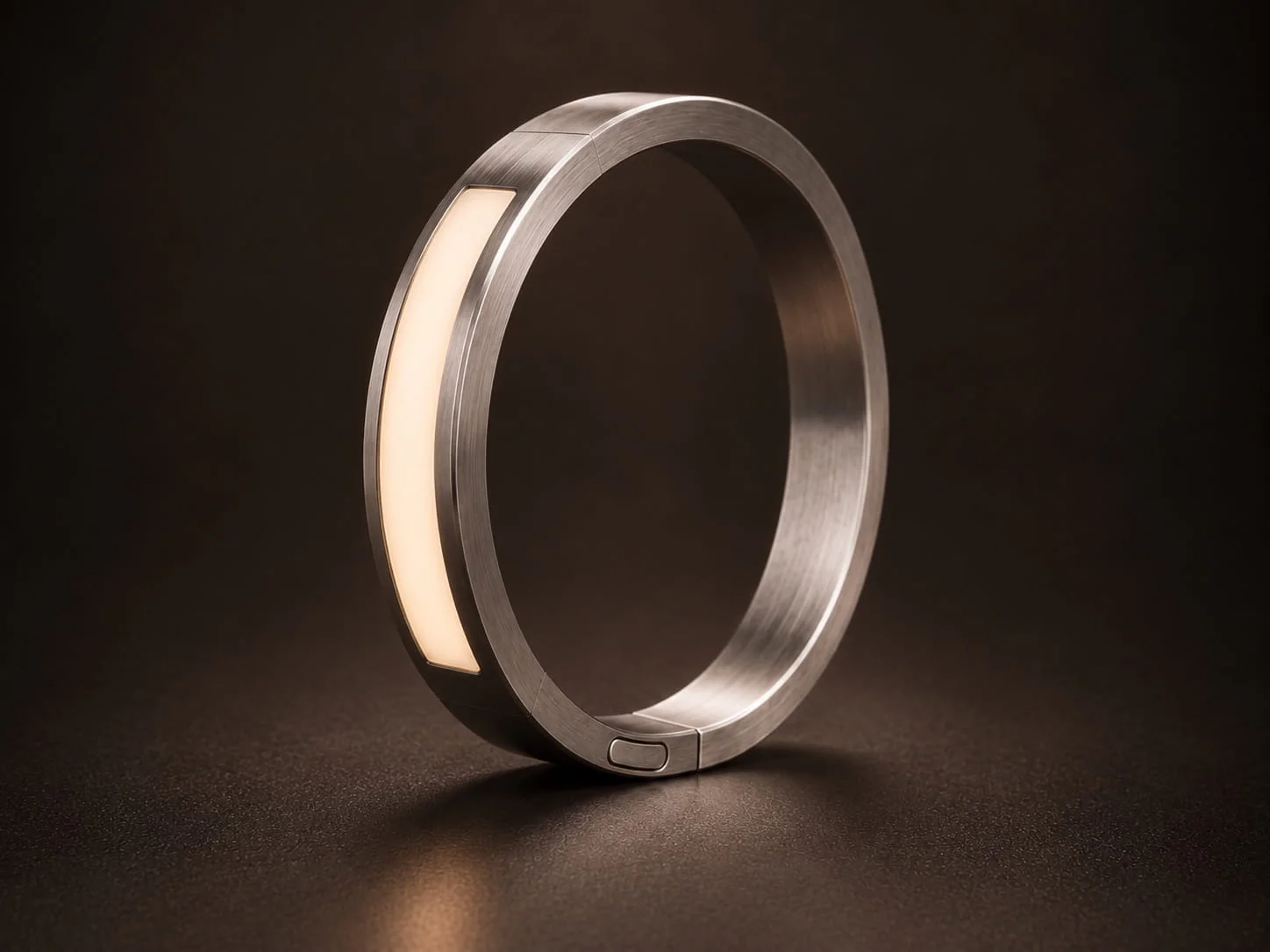 Inactive JUVEIL titanium bangle against a dark background.